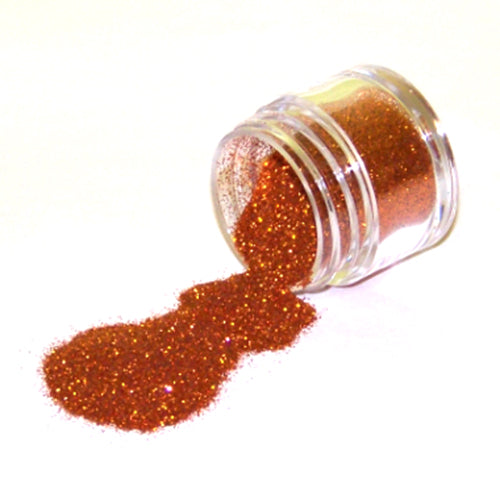Small clear jar tipped on its side spilling New Copper glitter dust onto a white surface, with fine shimmering copper particles and warm metallic sparkle throughout.