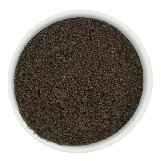 Top-down view of a white bowl filled with brown coarse sanding sugar crystals, showing chunky dark amber-brown granules with a subtle sparkling finish.