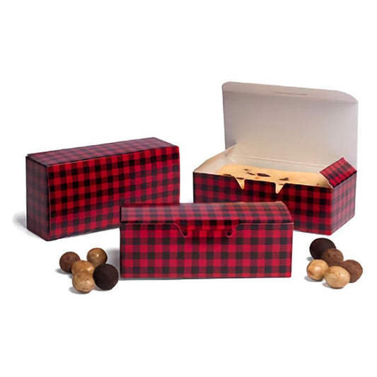 This image shows a set of Buffalo Plaid 1/2 lb candy boxes in a classic red and black checkered pattern. One box is open, displaying the white interior and suggesting it's ready to be filled with treats. Scattered in front of the boxes are various chocolate truffles, hinting at the type of confections these boxes are designed to hold. The background is neutral, focusing attention on the vibrant pattern of the boxes and the rich colors of the chocolates.