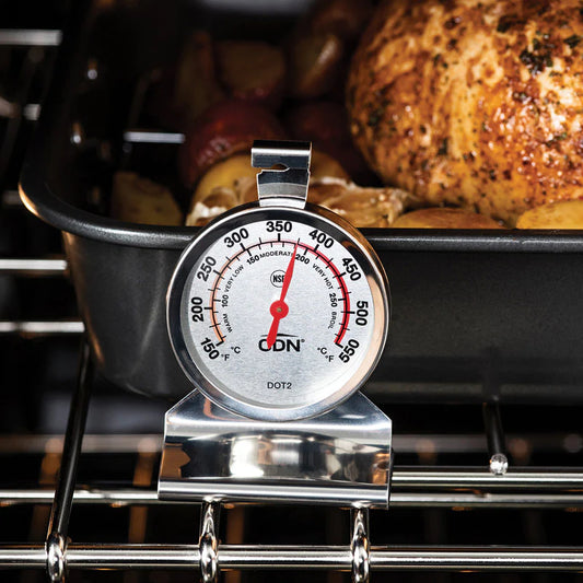 CDN oven thermometer standing on an oven rack in front of a roasting pan with poultry and potatoes.