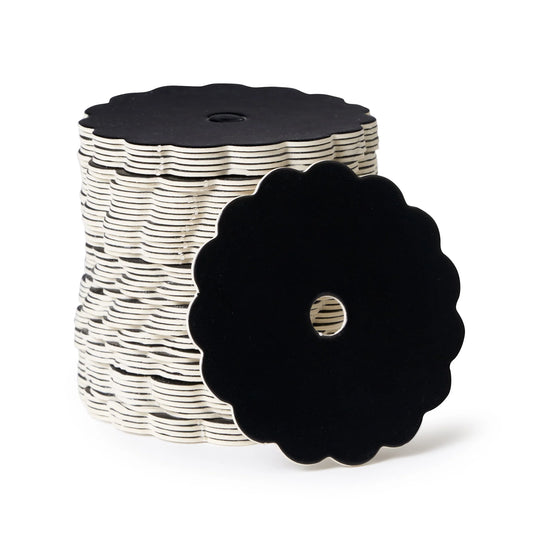 Stack of scalloped-edge black matte cake pop boards with center holes, shown with one board facing forward to display the floral-style edge.