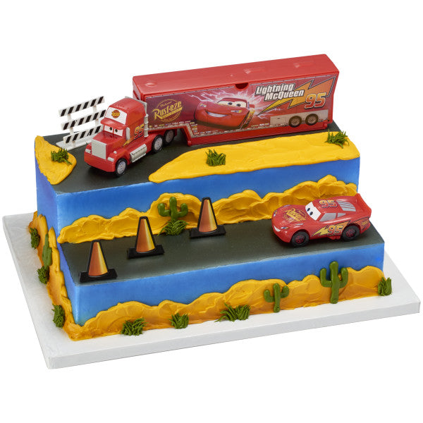 A tiered cake decorated with the Disney and Pixar's Cars Signature DecoSet®, featuring a highway design with Mack, Lightning McQueen, and cones.