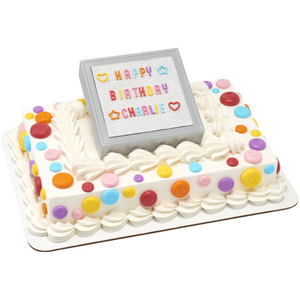 Rectangular cake decorated with a letter board topper spelling "Happy Birthday Charlie" in colorful letters.