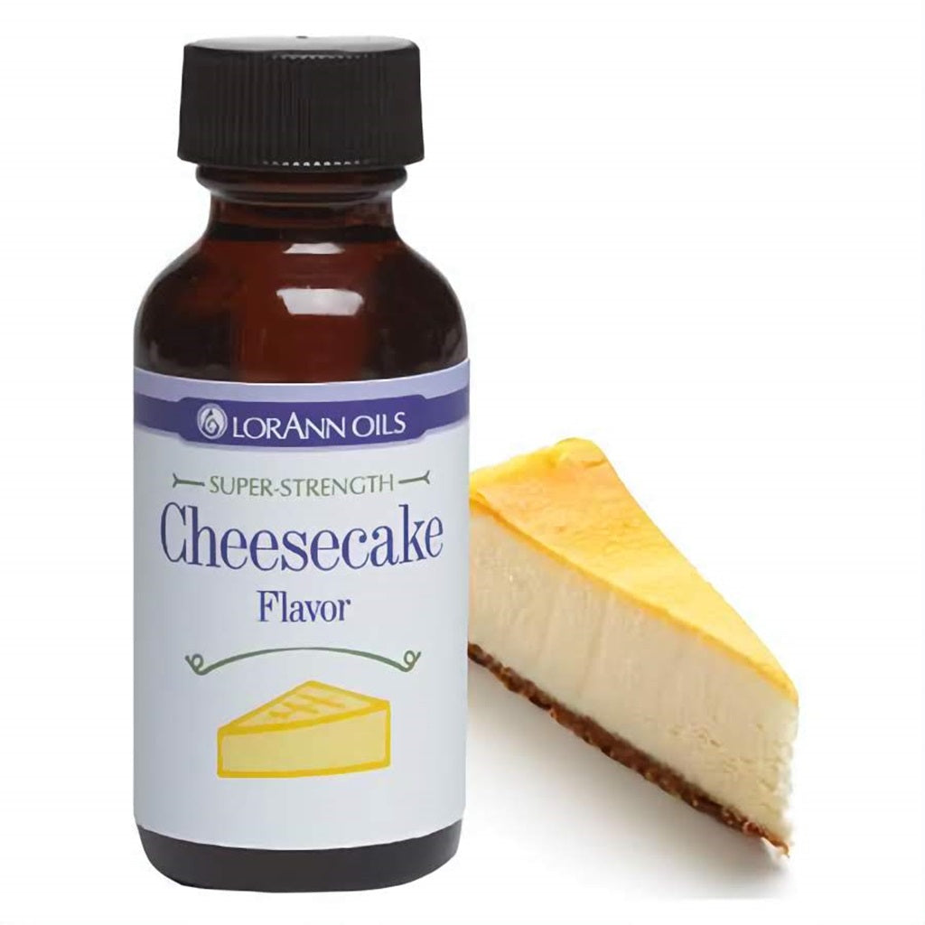 A 1 fl oz bottle of LorAnn Oils Super Strength Cheesecake Flavor, next to a creamy slice of cheesecake on a plate, illustrating the rich and tangy flavor profile.
