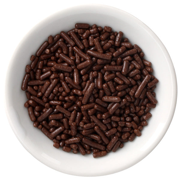 White bowl filled with deep chocolate-brown Natural Dyed Made Simply™ rod-shaped sprinkles, shown from above on a clean white background.