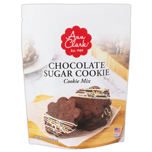 Front of Ann Clark Chocolate Sugar Cookie Mix package featuring chocolate cookies decorated with white drizzle and colorful sprinkles.