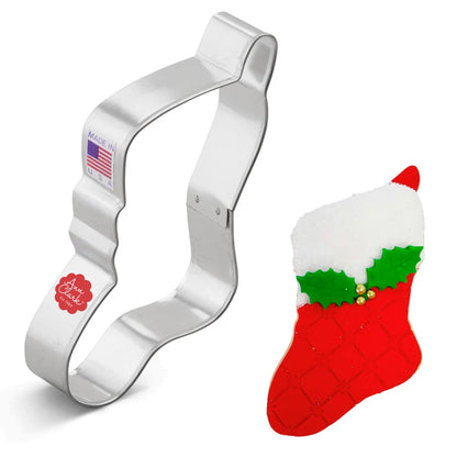 Christmas stocking cookie cutter alongside a decorated stocking cookie with red quilted icing, white sugar trim, and green holly leaves.