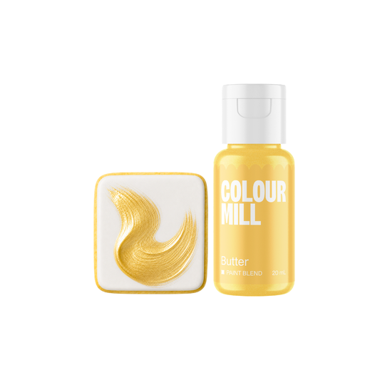 Colour Mill Butter Metallic Paint Blend bottle beside a white square confection decorated with a sweeping brushstroke of luminous gold edible paint.