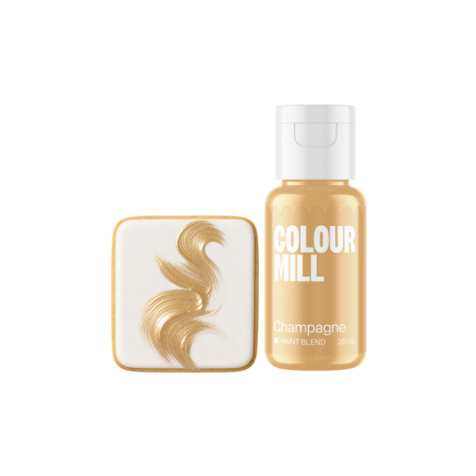 Colour Mill Champagne Metallic Paint Blend bottle beside a white square confection decorated with flowing brushstrokes of warm champagne-gold edible paint.