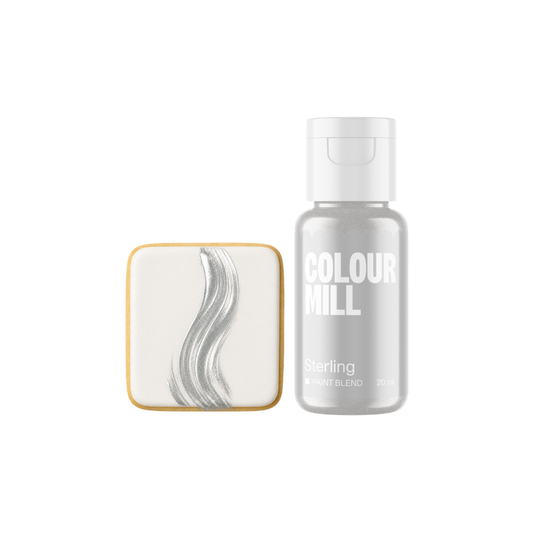 Colour Mill Sterling Metallic Paint Blend bottle next to a white square cookie decorated with a flowing silver-grey metallic brushstroke on a light background.