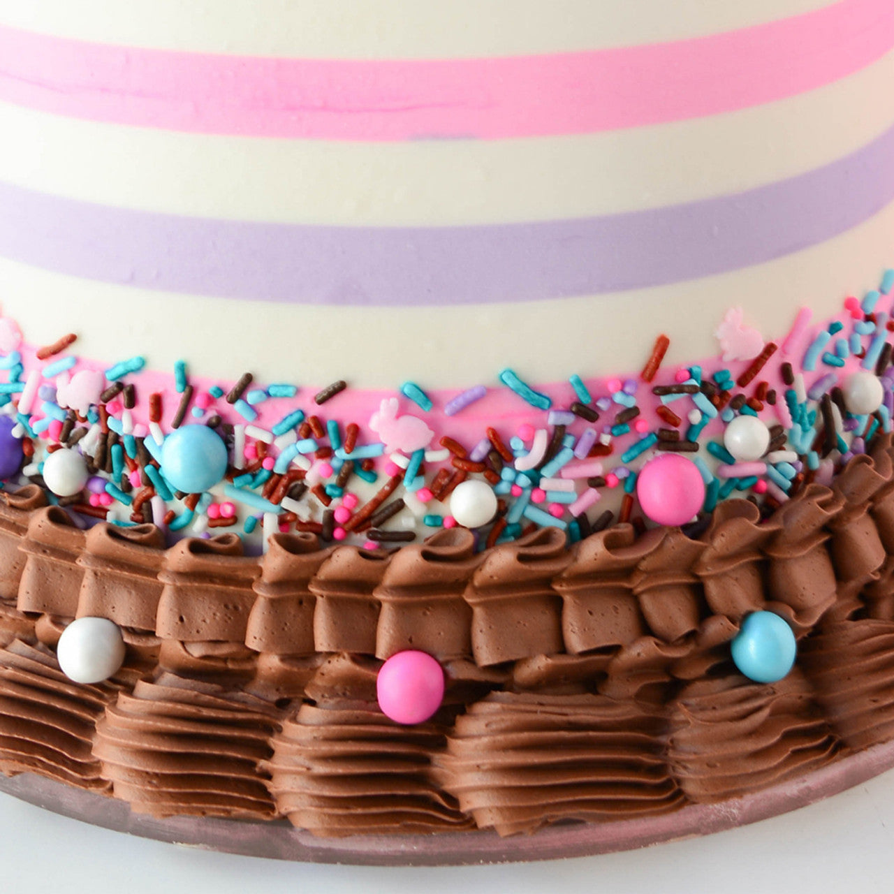 Decorated cake featuring chocolate brown buttercream tinted with Colour Mill Chocolate, pastel stripes, and colorful sprinkle mix