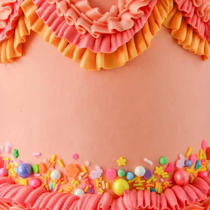 Cake decorated with buttercream ruffles and sprinkles in tropical tones using Colour Mill Coral.


