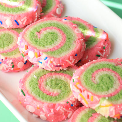 Spiral cookies decorated with Colour Mill Lime and pink coloring, covered in rainbow sprinkles.
