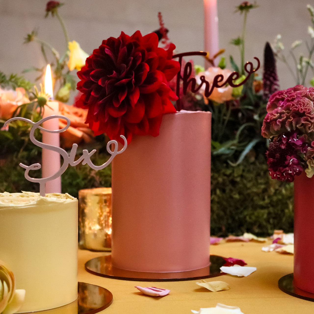 Elegant cakes decorated with Colour Mill Rust pigment, styled with florals and candlelight in a warm-toned setting
