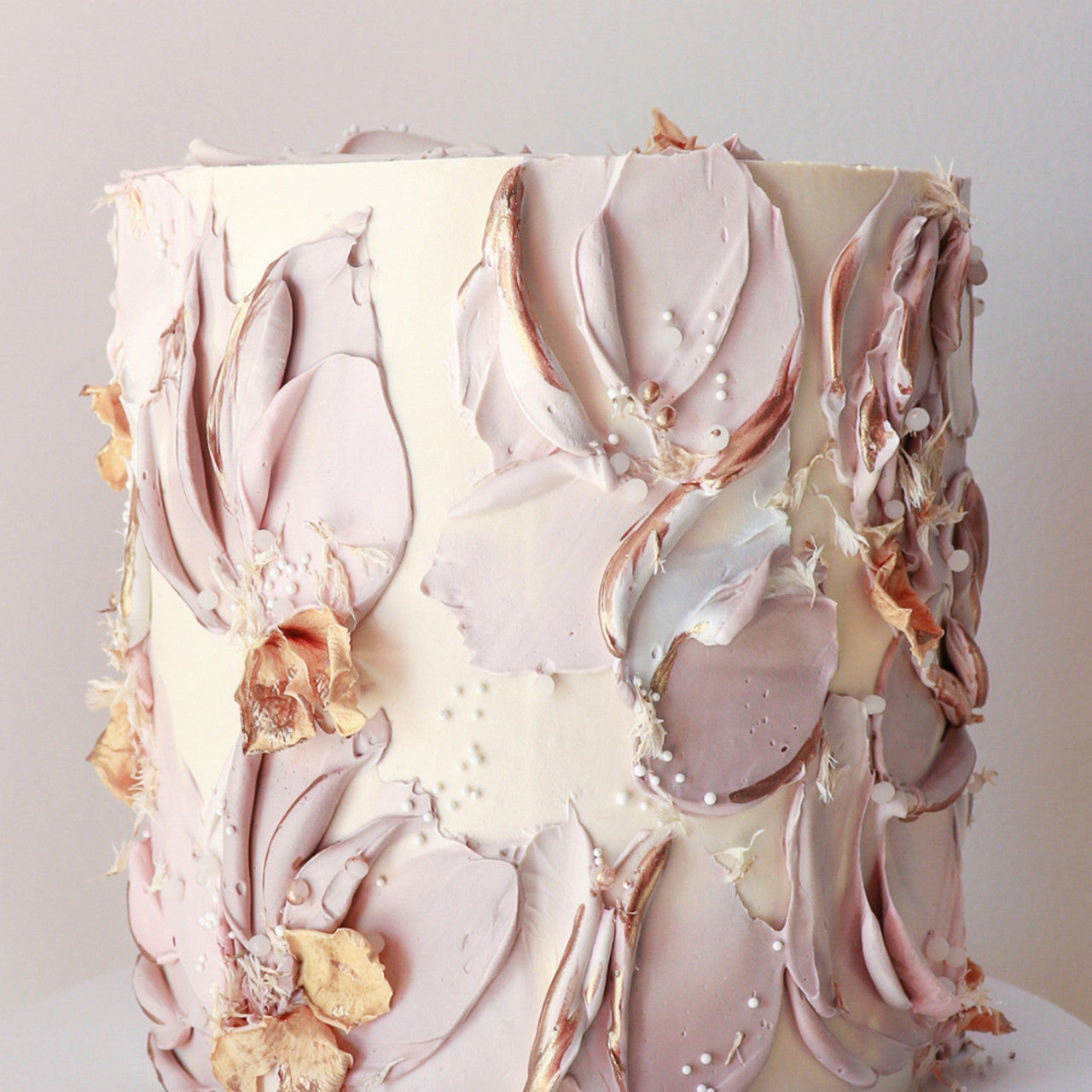 Cake decorated with soft taupe buttercream florals and dried accents