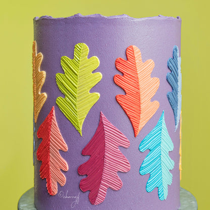 Cake decorated with bright violet buttercream and colorful fondant leaves, showcasing Colour Mill Violet in use