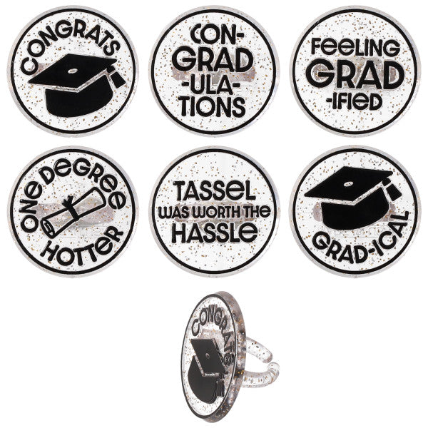 Six confetti graduation cupcake rings with black-and-white designs and phrases like “Congrats,” “Con-grad-ulations,” and “Tassel was worth the hassle,” shown on a white background with one ring displayed from the side.
