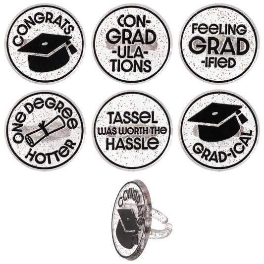 Six confetti graduation cupcake rings with black-and-white designs and phrases like “Congrats,” “Con-grad-ulations,” and “Tassel was worth the hassle,” shown on a white background with one ring displayed from the side.
