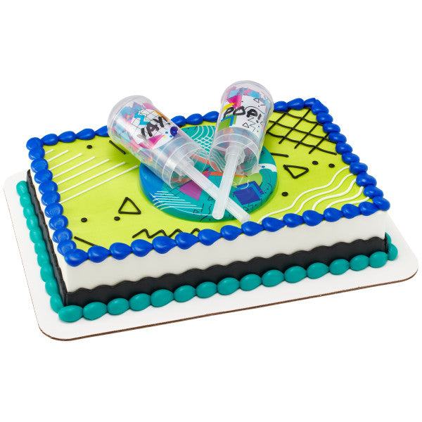 A rectangular cake decorated with bold colors and geometric designs, featuring the confetti launchers on top.