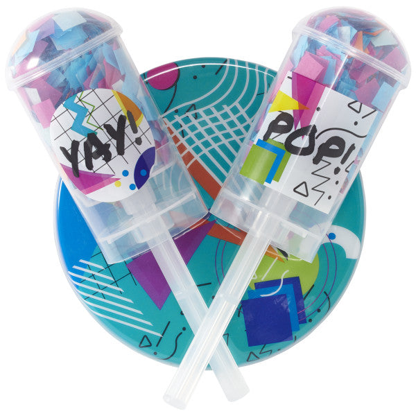 A three-piece cake topper set featuring two confetti launchers labeled "YAY!" and "POP!" along with a colorful geometric base.