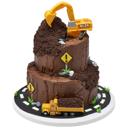 A two-tiered chocolate cake decorated to resemble a construction site, with edible "dirt" and toy construction vehicles.