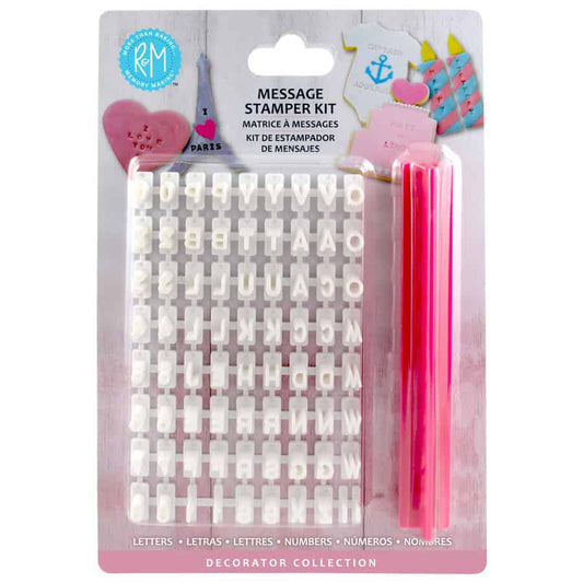 Retail package of a message stamper kit showing a white plastic letter and number set beside a bright pink holder, with sample stamped cookie designs on the header card.