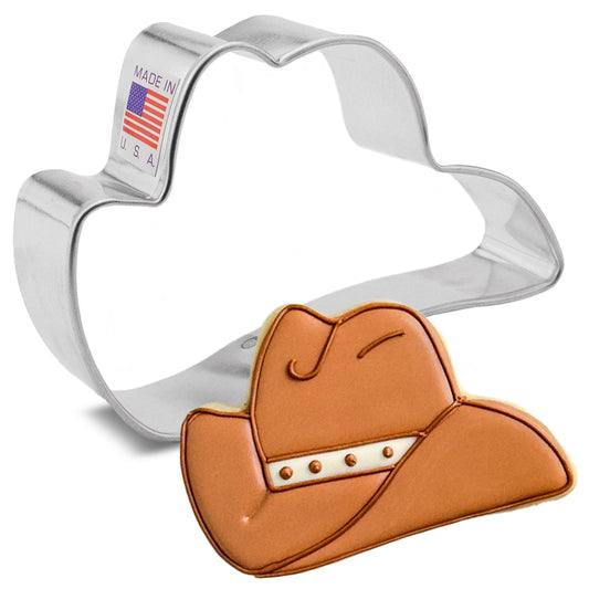 Silver cowboy hat-shaped cookie cutter shown beside a decorated cowboy hat cookie with tan icing, darker piped outline, a white hatband with small stud details, on a white background.