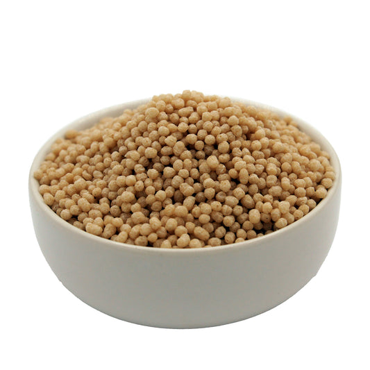 A white bowl filled with tiny, round crisp rice balls approximately 1/8" in diameter, light golden in color and piled high against a plain white background.