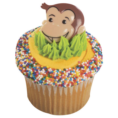 Vanilla cupcake decorated with yellow frosting, green piping, and a Curious George ring topper, surrounded by rainbow sprinkles.