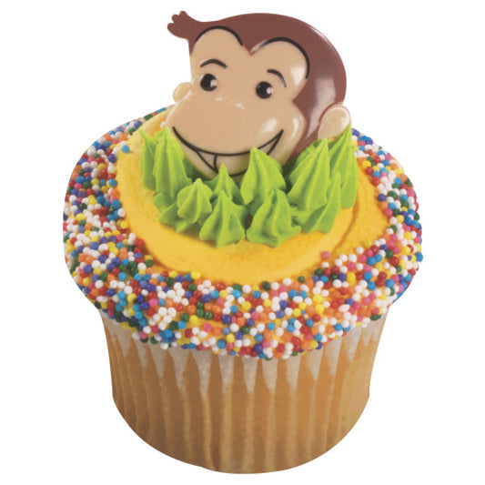 Vanilla cupcake decorated with yellow frosting, green piping, and a Curious George ring topper, surrounded by rainbow sprinkles.