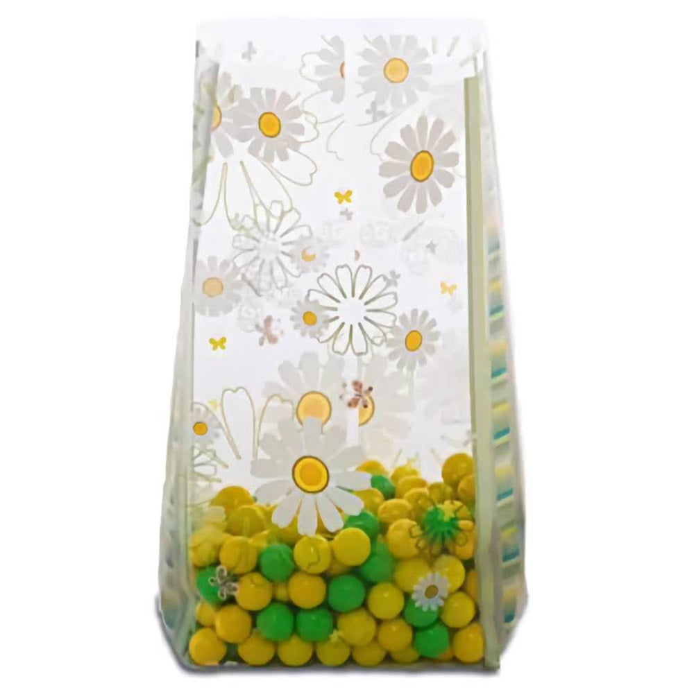 A medium-sized cellophane treat bag filled with bright yellow and green candies at the bottom. The bag is adorned with a delicate pattern of white daisies with yellow centers, and a few small bees scattered throughout. The transparent design with flowers creates a cheerful, spring-themed appearance, perfect for parties or as a sweet gift.