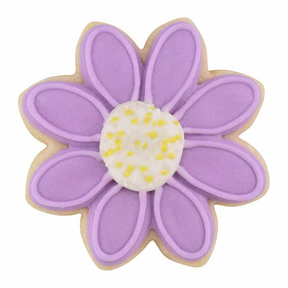 Decorated daisy-shaped cookie with purple icing, a white and yellow center, and intricate petal details.