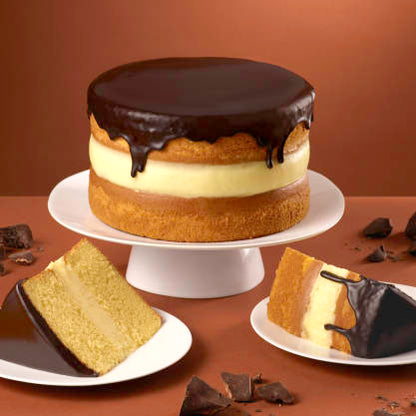 Layered cake with chocolate ganache on a white plate against a brown background