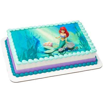 A vibrant ocean-themed cake with Ariel and her brush topper.