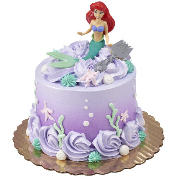 A dreamy, pastel cake topped with Ariel, surrounded by seashells and ocean-inspired decorations.