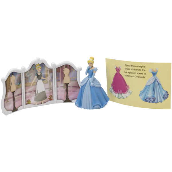 A three-piece cake topper set featuring a Cinderella figurine, a decorative backdrop, and two removable dress clings.