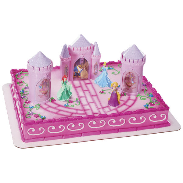 A rectangular cake decorated with the Disney Princess Castle Signature DecoSet®, featuring the castle, turrets, and princess figurines on a pink royal-themed design.