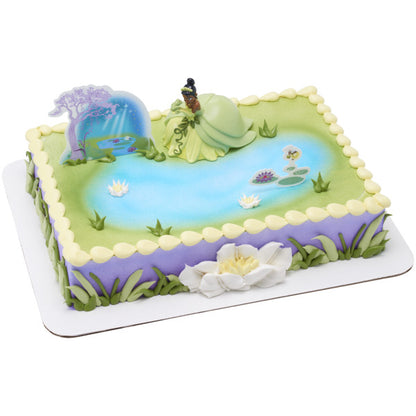 A pastel-colored cake featuring the Tiana figurine and scenic toppers creating a magical bayou setting.