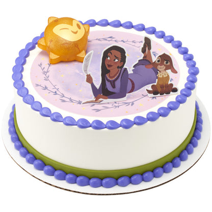 A round cake with a soft purple edible image, bordered in green and purple frosting, with the Disney's Wish Shining Star DecoSet as the centerpiece.