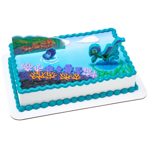 A rectangular ocean-themed cake with blue frosting, coral decorations, and Luca-themed cake toppers.