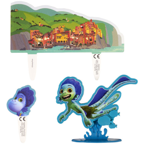 A cake decoration set featuring a Luca figurine, a scenic Italian coastal backdrop, and an additional character pick.