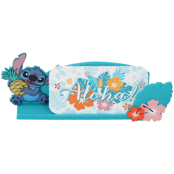 A Disney Stitch cake topper featuring Stitch with a pineapple, a floral message holder, and an "Aloha" sign.