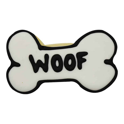 Dog bone-shaped cookie with white icing and 'WOOF' piped in bold black letters.