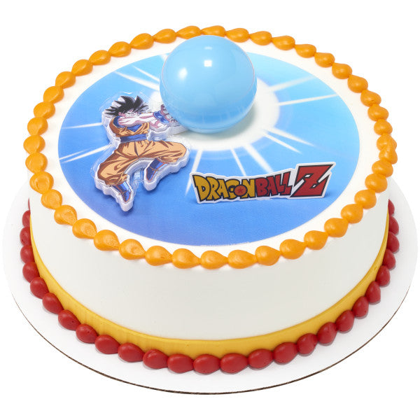 Round cake with a blue burst center image, Dragon Ball Z logo, and Goku topper next to a raised blue Spirit Blast sphere, finished with orange and red icing borders.