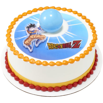 Round cake with a blue burst center image, Dragon Ball Z logo, and Goku topper next to a raised blue Spirit Blast sphere, finished with orange and red icing borders.