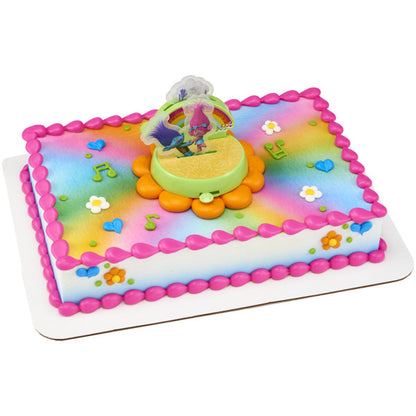 A rectangular cake decorated with the Trolls DecoSet®, featuring a rainbow-colored background and fun musical notes.