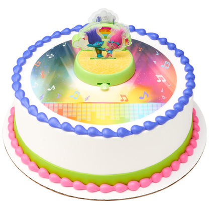 A round cake decorated with the Trolls DecoSet®, with a vibrant, music-inspired edible image and colorful piping.