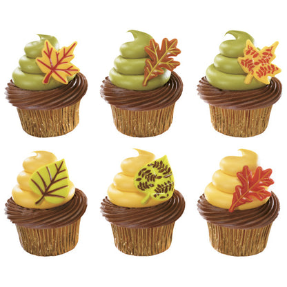 Cupcakes decorated with fall-themed frosting in brown, green, and yellow topped with colorful leaf-shaped cupcake picks.