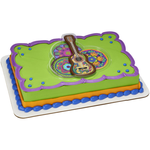 A sheet cake with a bright green base, purple trim, and the fiesta guitar topper set in the center.