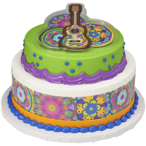 A two-tiered cake with bold colors and patterns, featuring the fiesta guitar topper set on top.